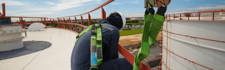 hse officer engineer performing risky job at height. he is wearing a hard hat ,a harness