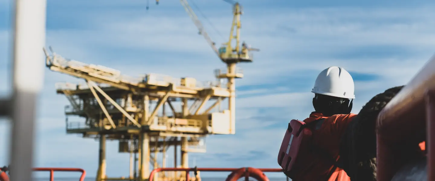 offshore worker looking into the horizon and an oil rig