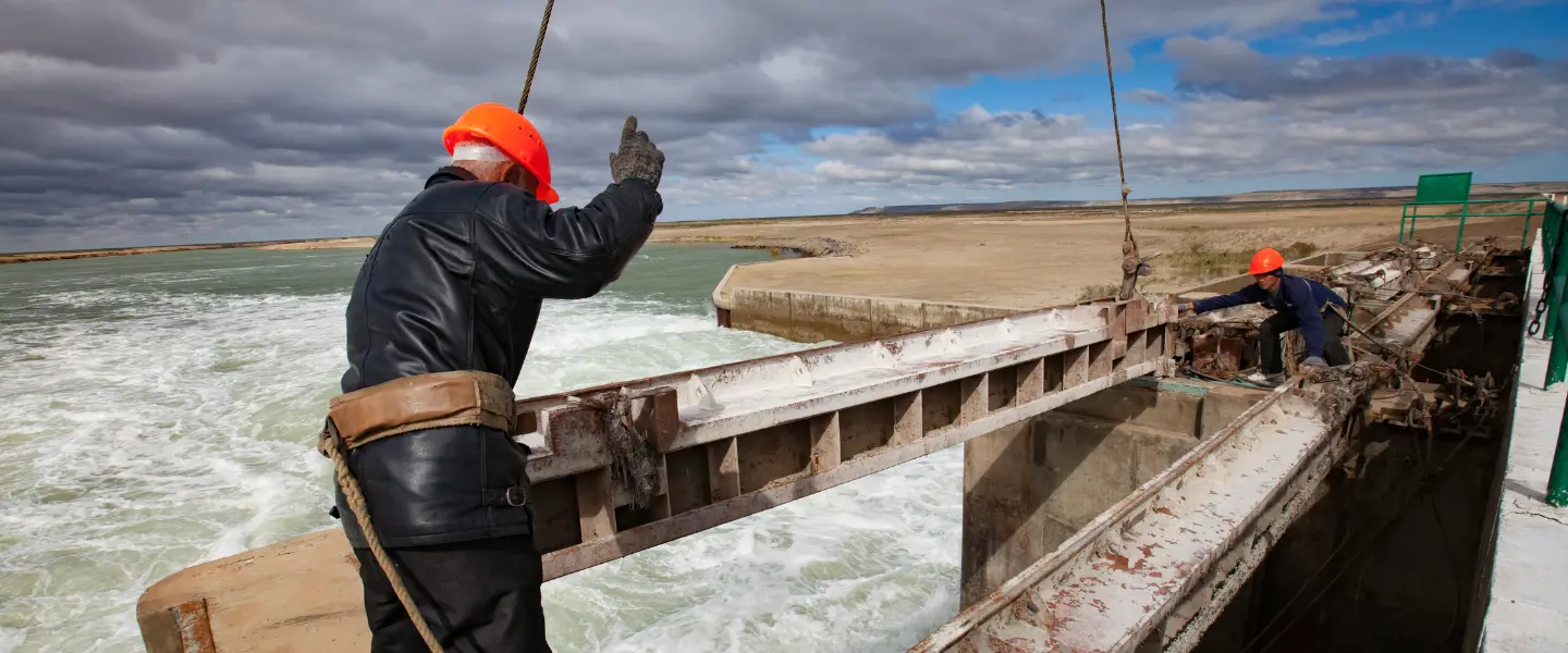 Two men assembling a hydro dam with orange hard hats