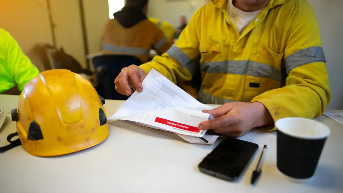 environmental professionals reading a safety documents with a hard hat on the table