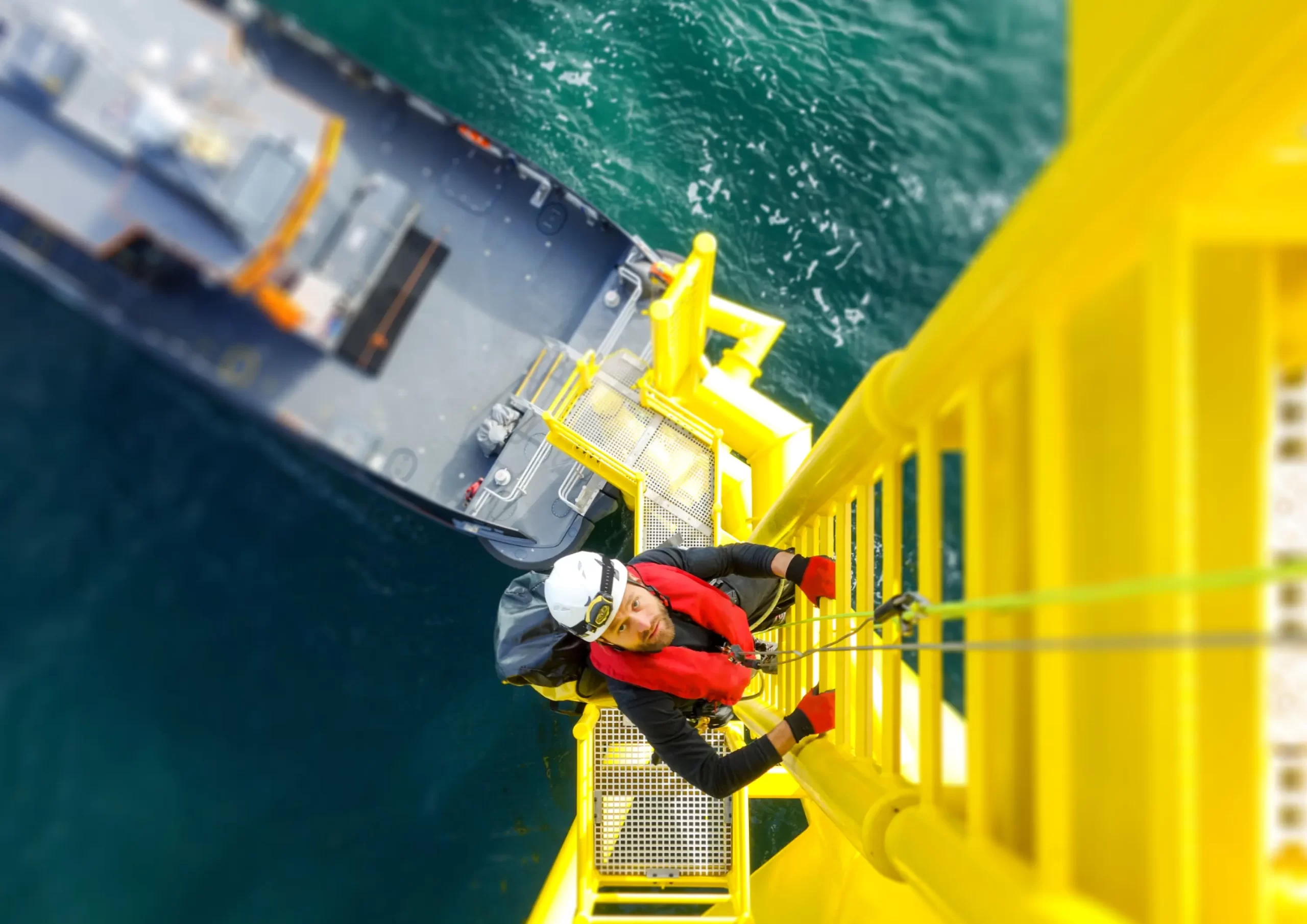 An offshore technician descends a ladder on an offshore platform