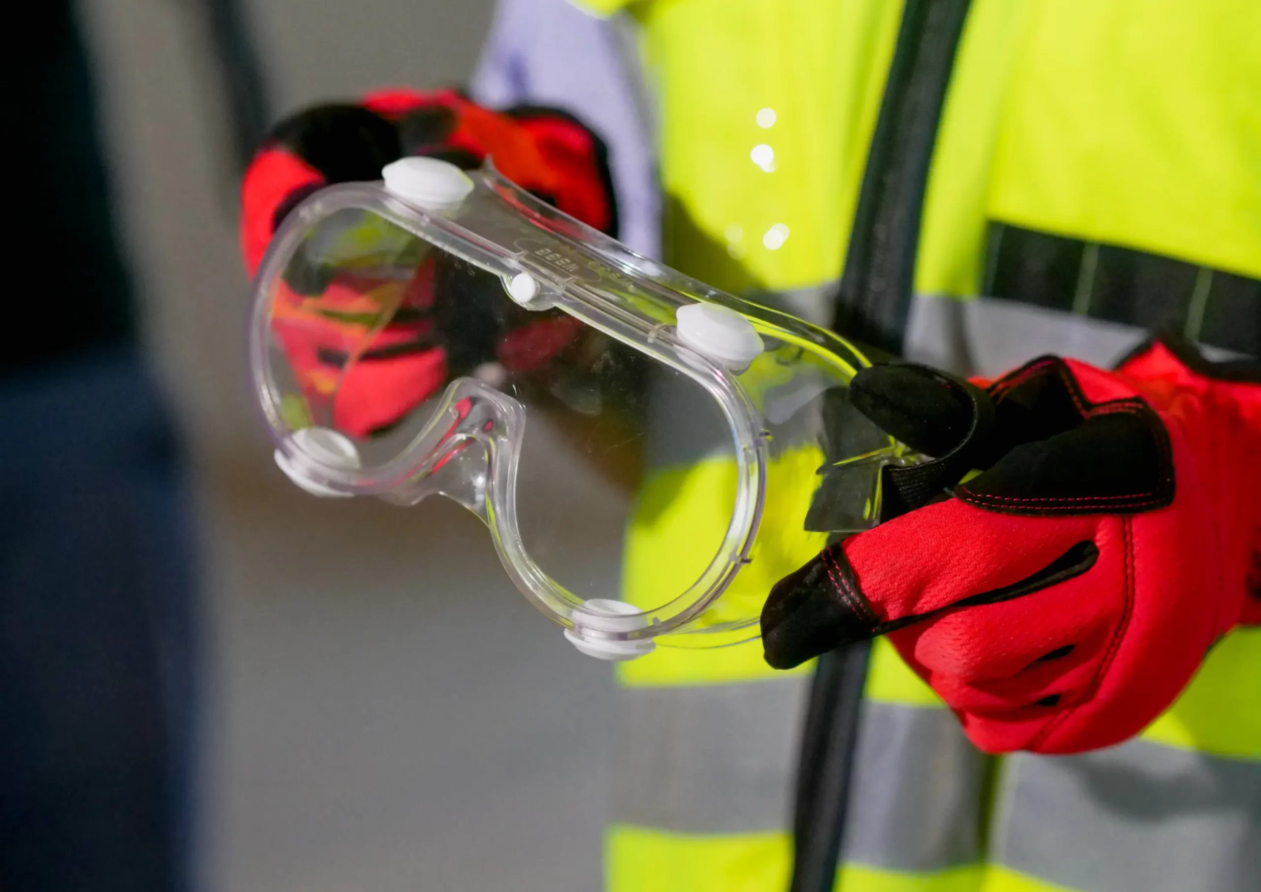 Worker in safety gear holding protective goggles during maritime training.