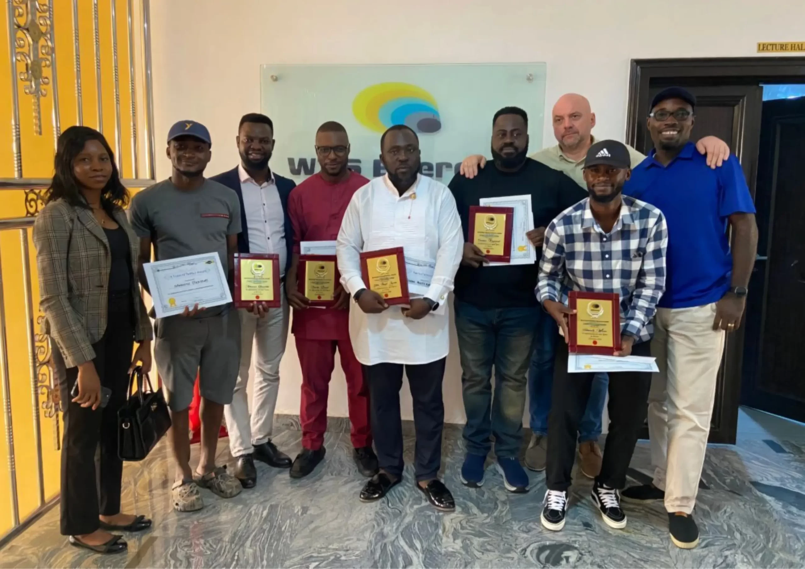 Group of participants holding certificates and plaques after completing training services in Nigeria.