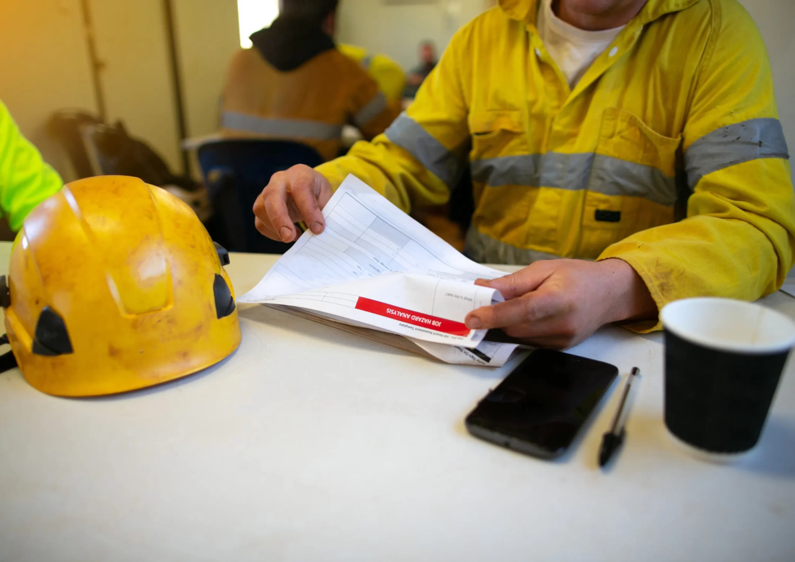 Worker reviewing job hazard analysis documents at a table, illustrating safety planning in operations and maintenance services in Kenya.