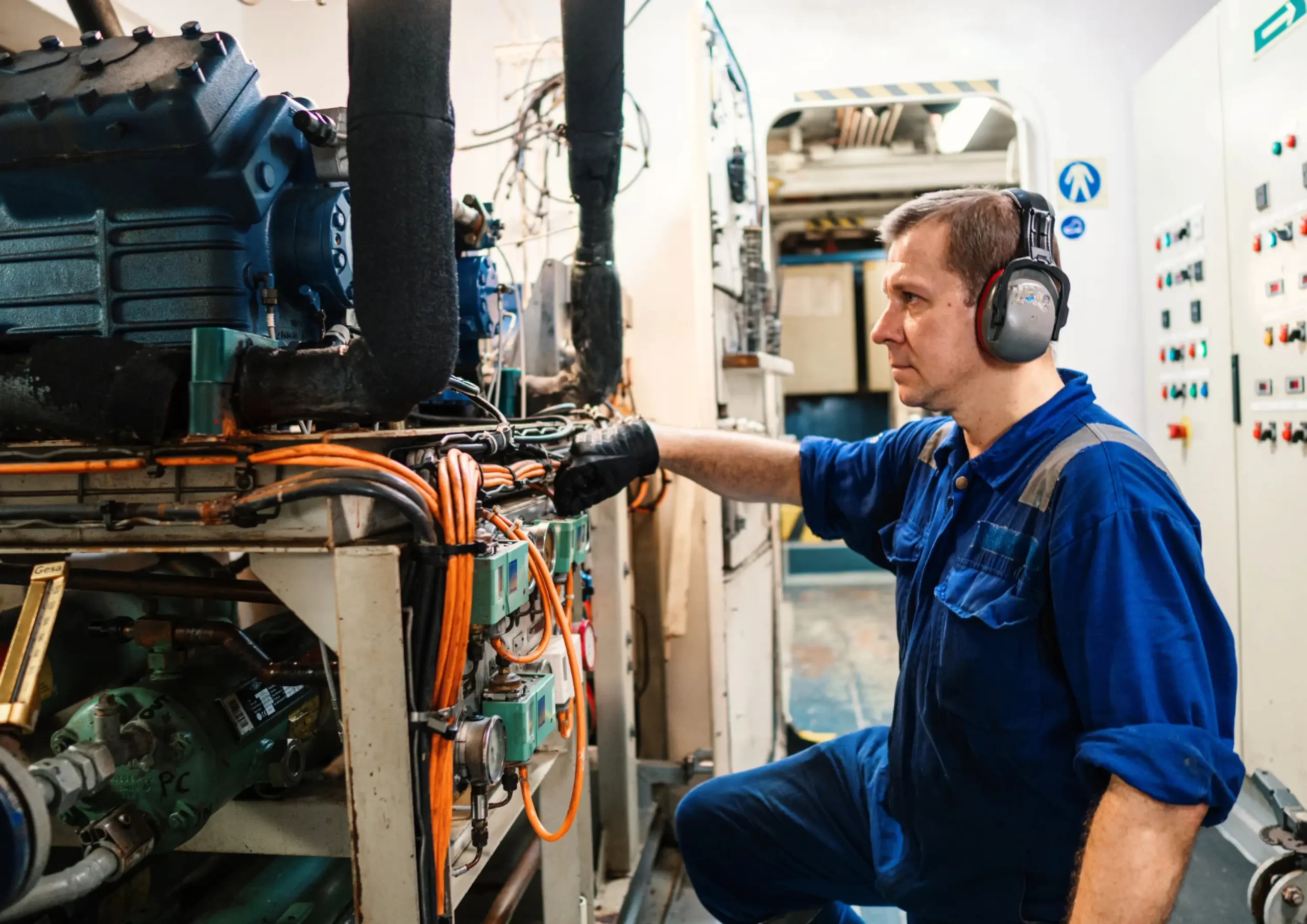 Technician wearing hearing protection inspects industrial machinery, highlighting operations and maintenance in Kenya.