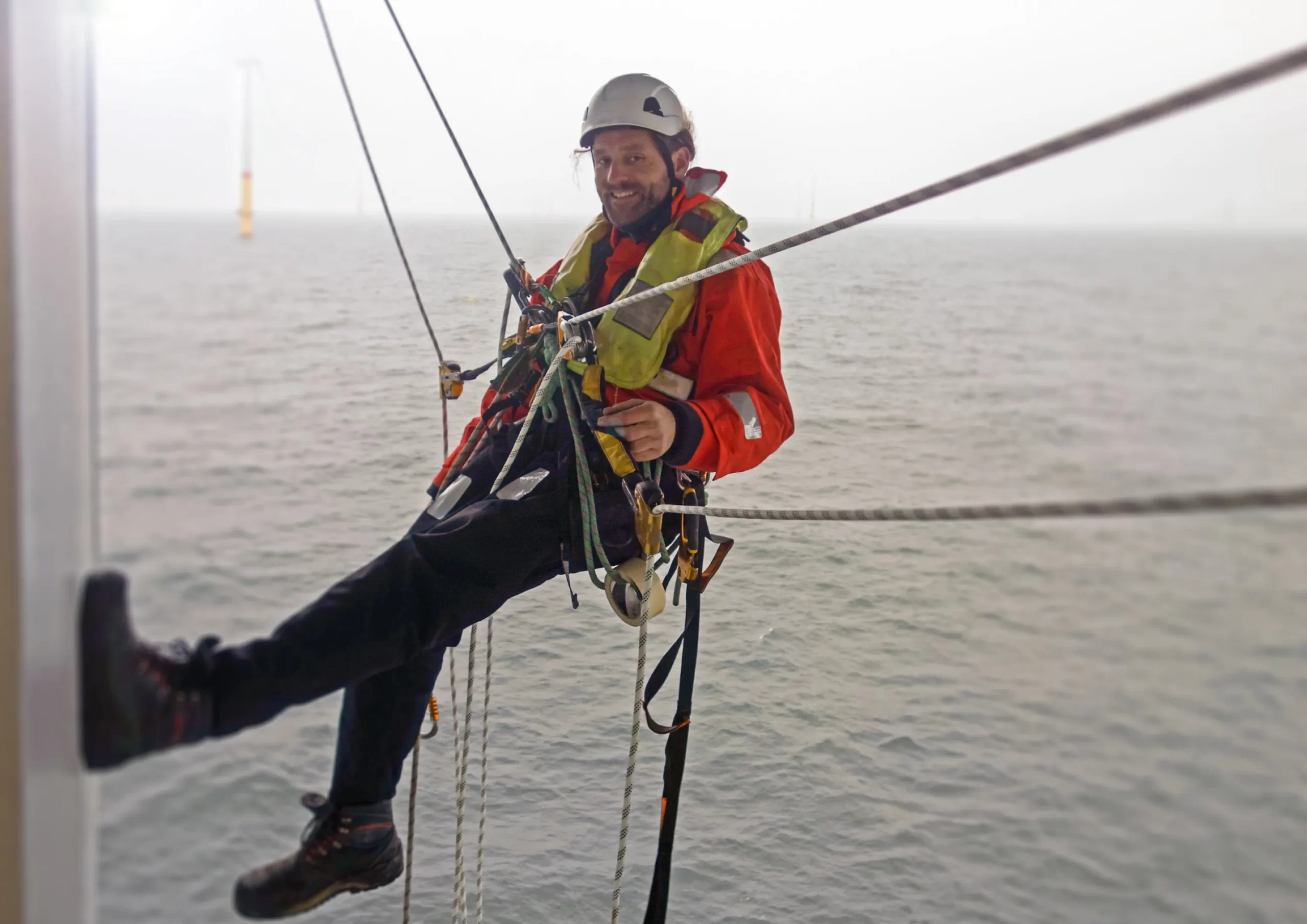 Rope access technician suspended over water, engaged in offshore operations and maintenance in Kenya.